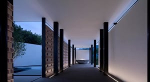 A modern interior corridor featuring minimalist design, concrete walls, and floor-to-ceiling lamp