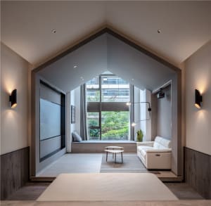Modern, minimalist living room with a high, pitched ceiling, large windows, and a white sofa.