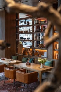Industrial-style restaurant interior featuring wooden tables, leather chairs, and upholstered seating.