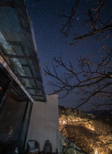 Minimalist stone concrete architectural exterior at night with starry sky.