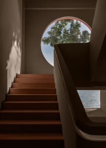 A staircase leading to a garden view through a circular window.