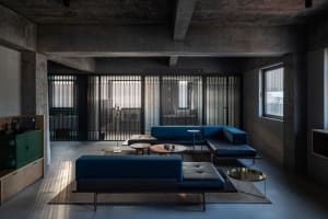Modern industrial living room with concrete walls and ceiling beams.