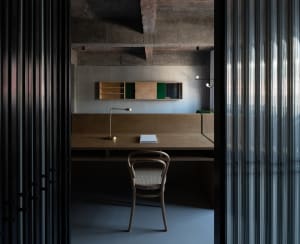 Industrial-style workspace featuring a wooden desk, chair, and minimalist shelving unit.