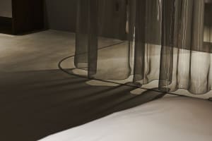 A minimalist interior with transparent curtains allowing natural light to filter through.
