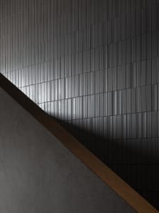 A minimalist interior featuring grey tiles with a diagonal light and shadow pattern.