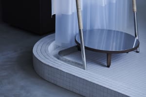 A modern bathroom featuring a circular metal tray and a white tiled floor with a circular ceramic tile design.