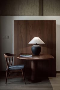A modern home office with a wooden desk, chair, and lamp.