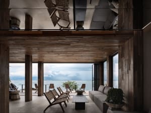 A modern living room featuring wooden walls and floor, with a view of the sea.