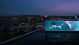 A modern swimming pool with glass walls overlooking a cityscape.