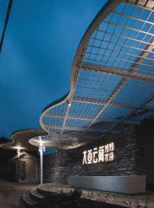 A modern entrance featuring a metallic grid and stone wall.