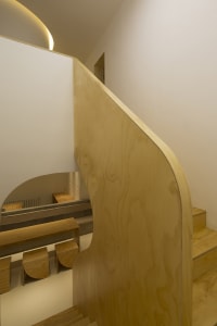 A modern wooden staircase with curved wooden walls and steps.