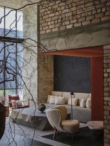 A modern living room with exposed concrete walls, a large sofa, and minimalist furniture.