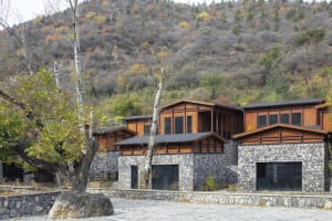 Modern residential houses with rock walls and wooden accents nestled in a valley.