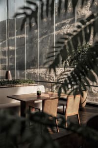A modern restaurant seating area with wooden furniture and large windows overlooking a mountainous landscape.
