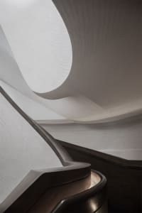 A modern staircase with wooden railings and a curved design.
