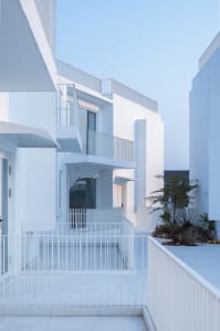 Modern residential exterior with concrete walls and white railings.