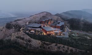 A resort with modern architecture, featuring wooden structures with glass windows at dusk.