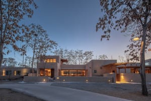 Modern residential exterior with concrete walls and warm interior lights.