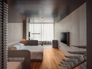 Modern bedroom with minimalist design, featuring a sleek metal bed frame and wooden flooring.