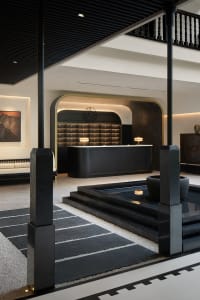 Modern, minimalist lobby reception area with a concrete material design and a central water feature.