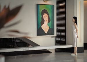 A minimalist modern living room featuring a woman with brown hair dressed in green standing in front of a painting of a woman