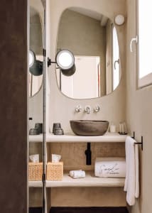 Minimalist bathroom with a concrete countertop and sink, white towels, and decorative elements.