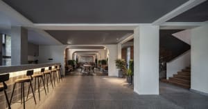 Modern coffee shop interior with concrete flooring, brick structural columns, and potted green plants