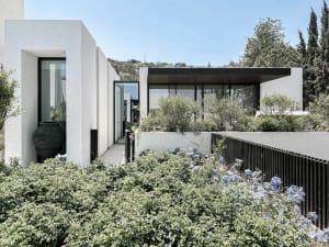 Modern residential home with white concrete exterior and large glass windows.