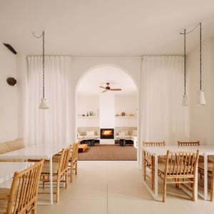 A modern living room with white and beige furniture and a central fireplace.