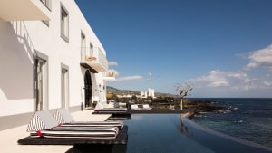 A modern resort with a sea-view poolside reception area, featuring a concrete building with a sleek design.
