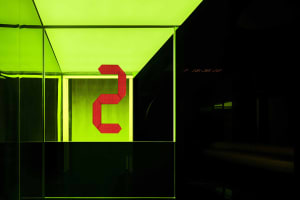 A digital display showing the number 2 in red, illuminated against a bright green background.