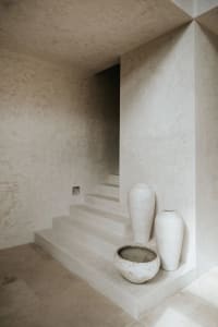 A minimalist stairwell with concrete steps, walls, and vases in a neutral color palette.
