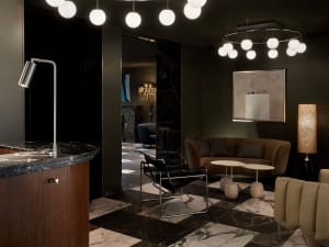 A modern living room with a marble floor, a beige sofa, and a black chair.