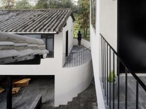 A modern house with white walls and concrete roof tiles, featuring a curved balcony.