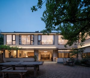 A modern minimalist residential space with white-rendered cement walls and large windows.