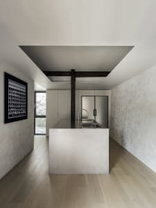 Modern kitchen with minimalist design featuring concrete countertops and stainless steel appliances.