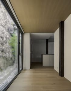 Modern minimalist kitchen with wooden flooring and glass walls