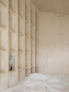A minimalist bedroom with wooden walls and shelves.