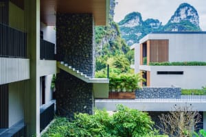 Modern residential exterior featuring concrete, stone, and glass materials.
