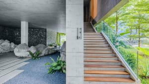 Concrete staircase with wooden steps and glass railing.