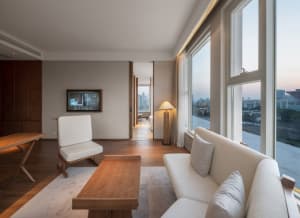 A modern living room featuring a white sofa, wooden coffee table, and minimalist design.