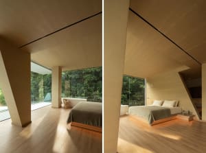 Modern bedroom featuring a wooden platform bed with a backdrop of a forest and large glass windows.