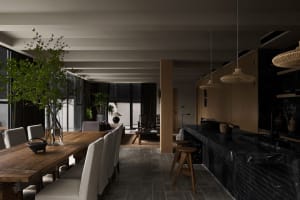 Modern dining area featuring a wooden table with upholstered chairs and a black marble kitchen counter.
