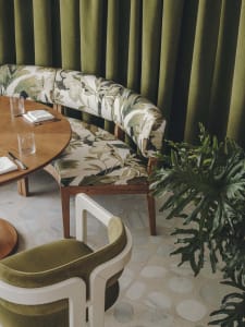Modern restaurant interior with terrazzo tiles and green curtains.