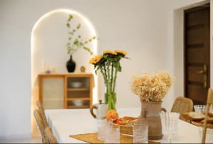 A well-designed dining room featuring a table adorned with ceramic vases, glasses, and a tray of bread and fruit, with a wood