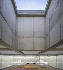 Modern minimalist interior space with concrete walls, featuring a concrete floor and a skylight.