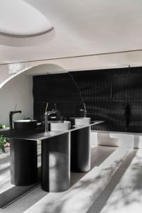 A modern, industrial-style bathroom with metallic elements and concrete sinks.
