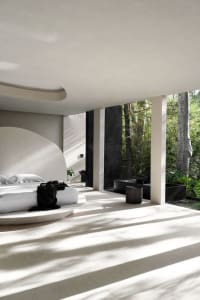 Modern minimalist bedroom featuring concrete flooring with natural light streaming in from a garden view.