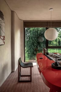 Industrial dining room featuring a sleek, metallic counter and simple, black chairs by a large window.