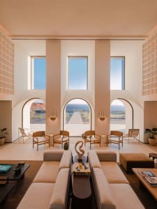 Modern hotel lobby featuring sleek, minimalist design with concrete floors, glass walls, and natural light.